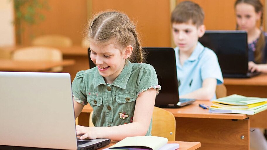 Schülerinnen und Schüler arbeiten an Laptops in der Schule. 