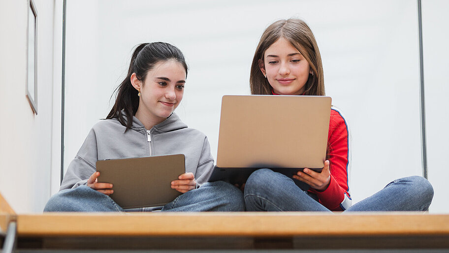 Mädchen sitzend im Treppenhaus mit Laptop