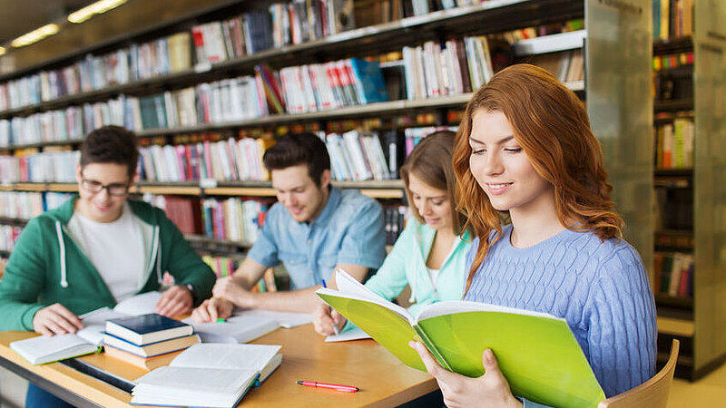 Junge Menschen, die zusammen in einer Bibliothek lernen