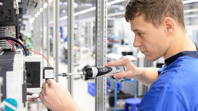 Junger Lehrling in Fabrik montiert elektronische Bauteile