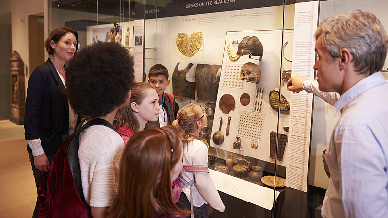 Schulklasse bekommen bei einer Führung durch ein historisches Museum Artefakte erklärt