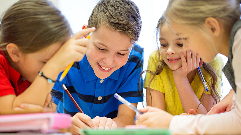 Junge Schülerinnen und Schüler, die gemeinsam etwas aufschreiben