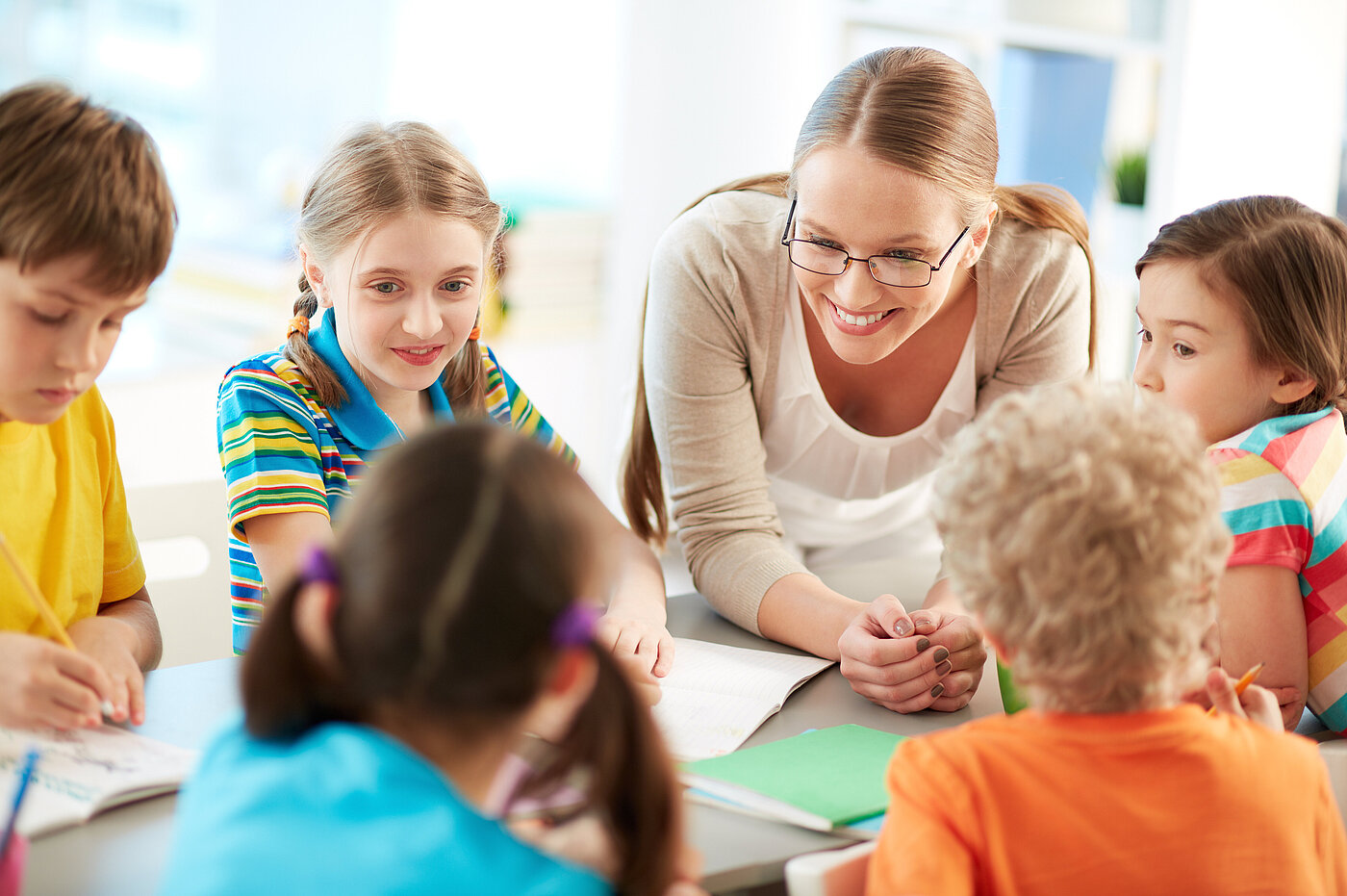 Lehrerin mit Schülern bei Gruppenarbeit im Gespräch