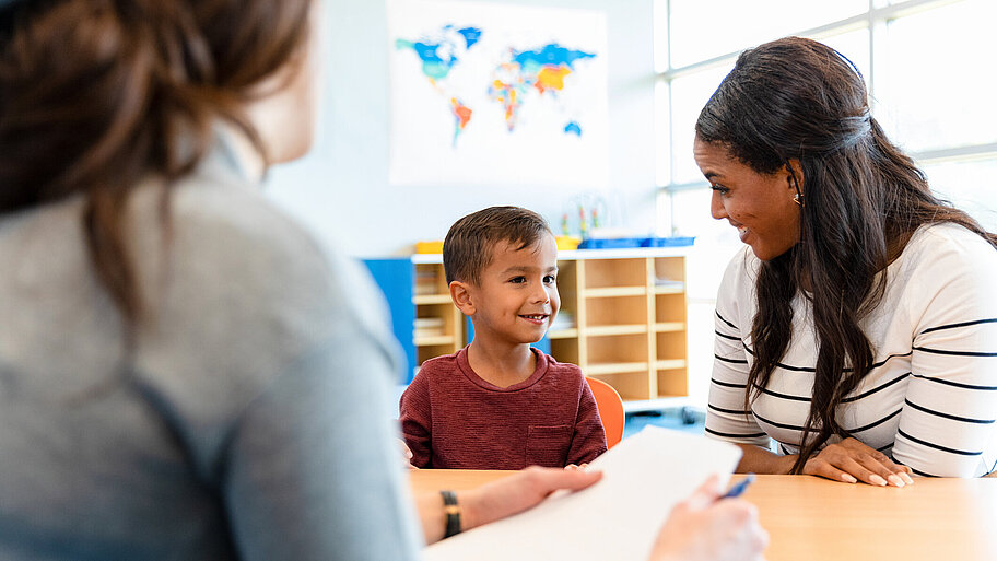 Mutter und Sohn sitzen im Klassenzimmer zum Beratungsgespräch