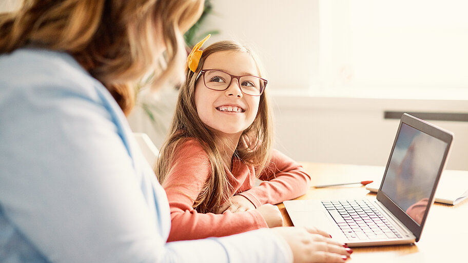Lehrerin/Mutter mit Mädchen gemeinsam am Laptop
