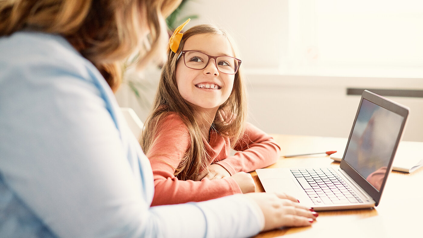 Lehrerin/Mutter mit Mädchen gemeinsam am Laptop