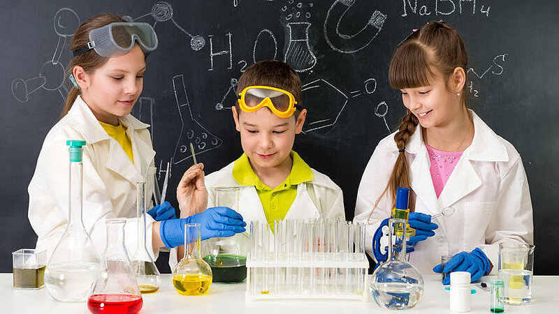 Drei Schüler, die mit Flüssigkeiten in Reagenzgläsern experimentieren