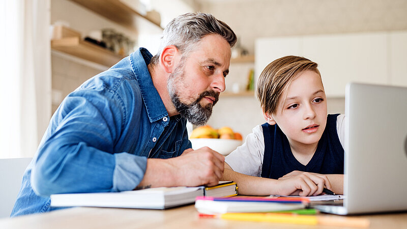 Vater und Sohn lernen gemeinsam vor dem Laptop