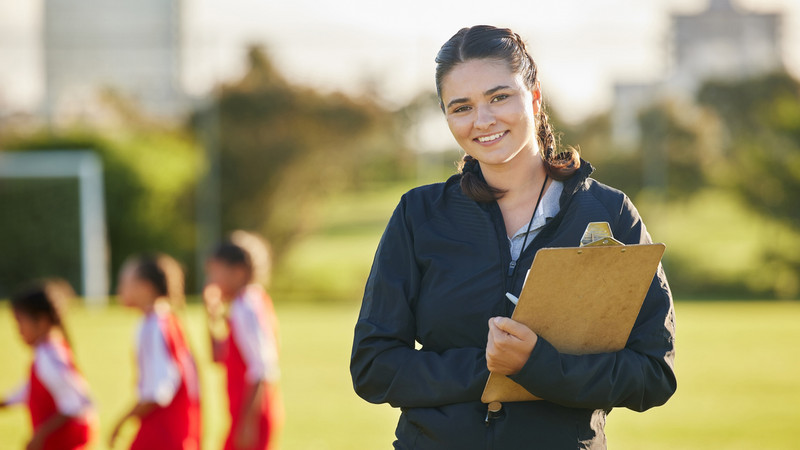 Trainerin auf einem Fußballplatz mit Klemmbrett