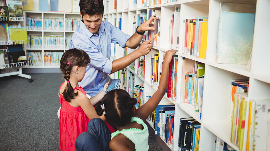 Drei Kinder vor einem Bücherregal