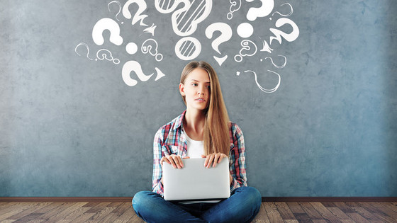 Sitzende, nachdenkliche Schülerin, symbolisiert durch viele Fragezeichen