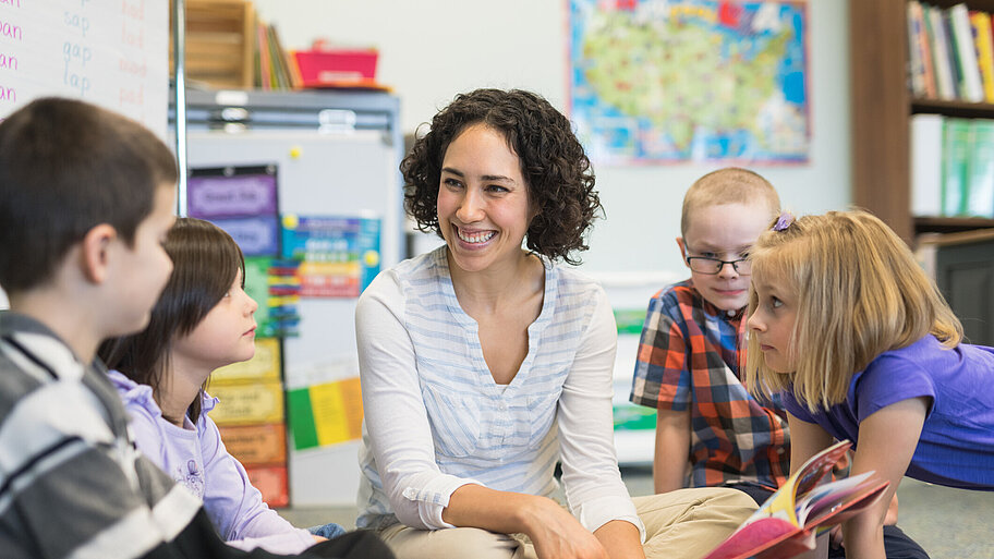 Frau liest Kindern im Klassenzimmer vor