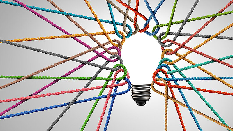 Glühbirne umrandet mit verschieden farbigen ineinandergeflochtenen Fäden als Metapher für kreative Teamarbeit und Diversity-Strategie