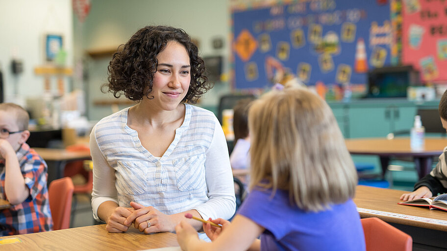 Lehrerin und Schülerin sitzen sich während des Unterrichts an einem Tisch gegenüber