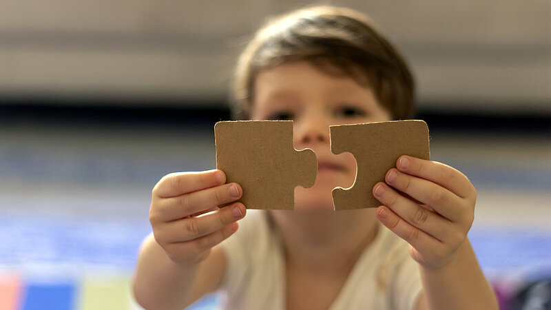 Kind hält zwei große Puzzleteile in die Kamera