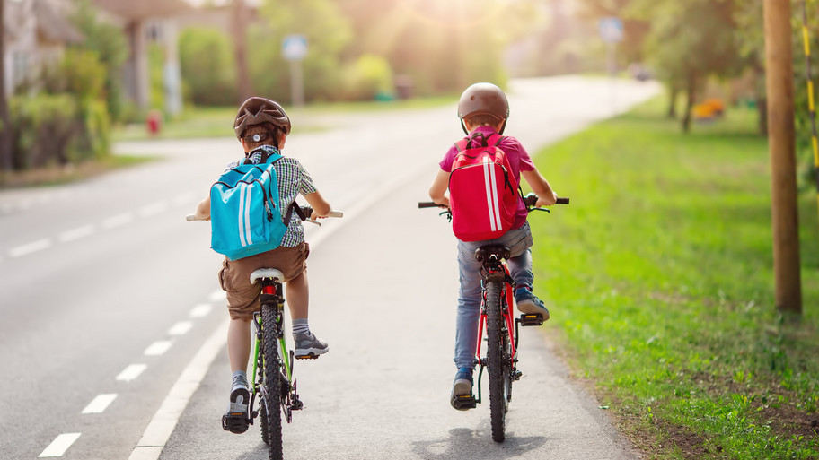 Two boys with backpacks on bicycles going to school.