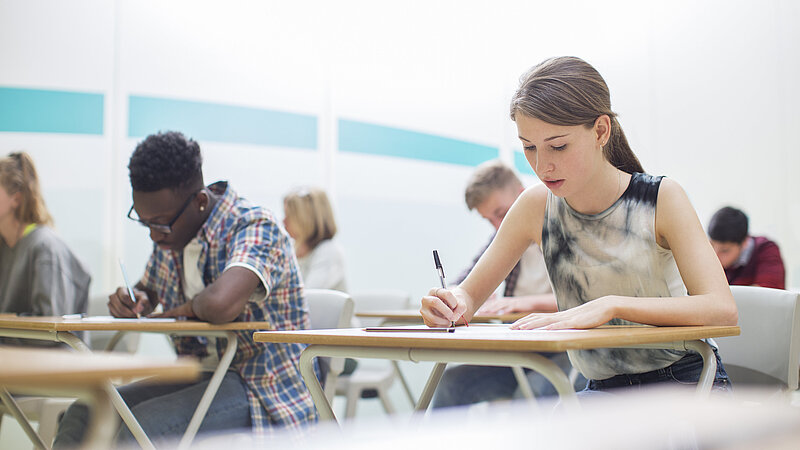 Schülerinnen und Schüler schreiben im Klassenzimmer eine Prüfung