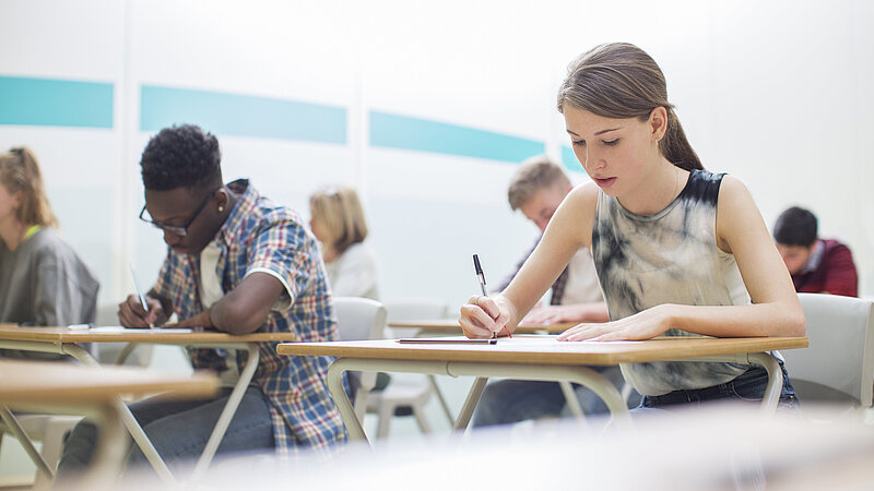 Schülerinnen und Schüler schreiben im Klassenzimmer eine Prüfung