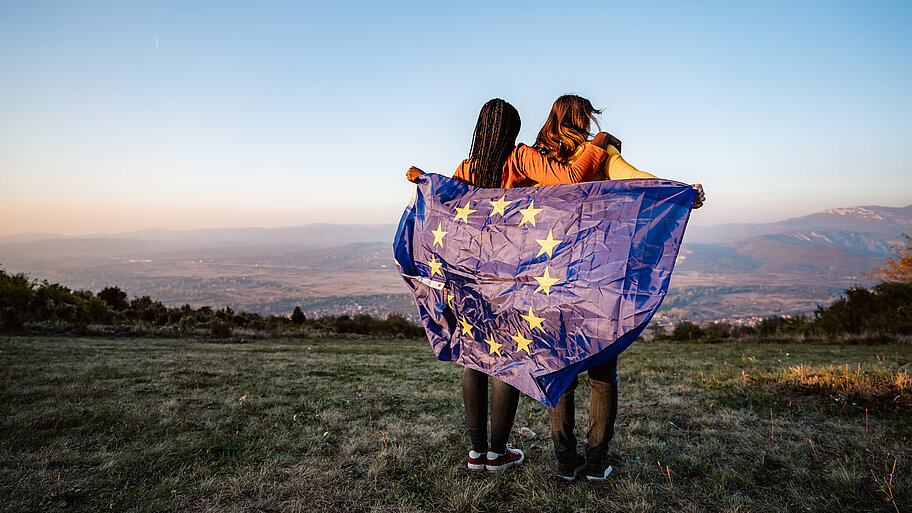 Zwei junge Frauen mit der Flagge der Europäischen Union auf der Wiese.
