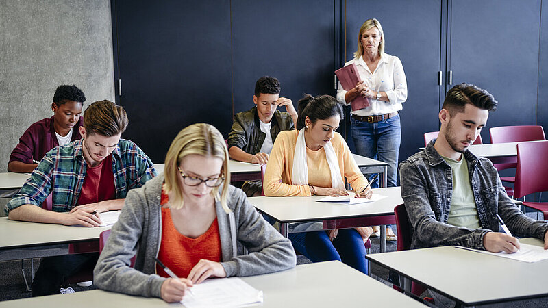 Junge Menschen bei schriftlicher Prüfung im Klassenraum