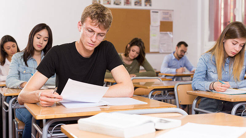 Junger Mann schreibt Test im Klassenzimmer