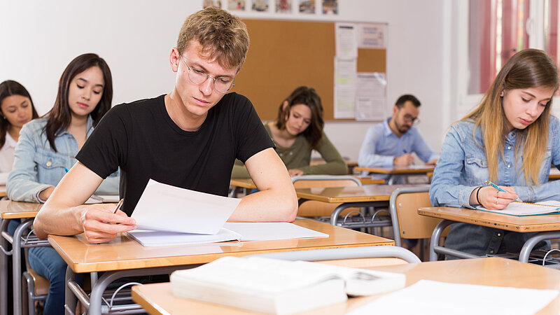 Junger Mann schreibt Test im Klassenzimmer