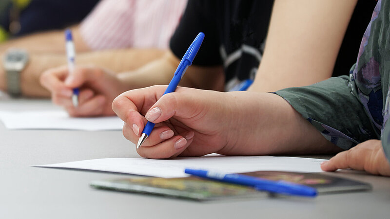 The girls write with fountain pens on sheets of paper. Concept for college exam, filling out forms and questionnaires. Web banner. Close-up