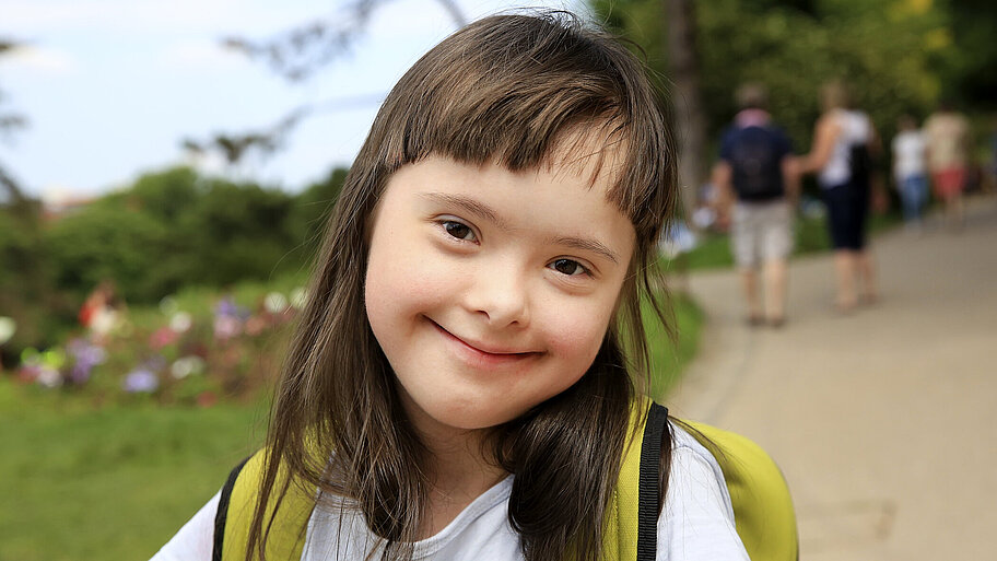 Nahaufnahme eines lächelnden Mädchens mit Downsyndrom im Park