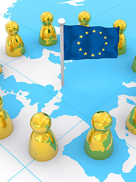 Kleine Figuren die einen Kreis auf einer Landkarte um Europa bilden