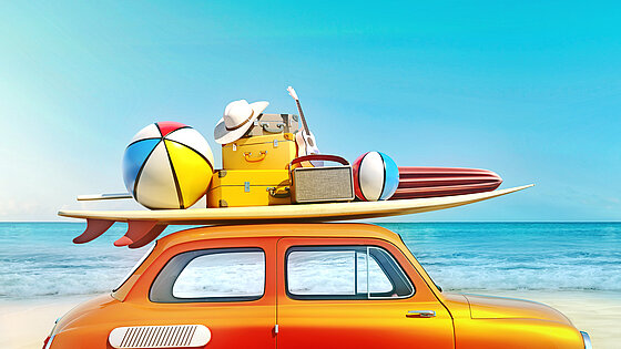 Kleines Retro-Auto mit Gepäck und Strandausrüstung auf dem Dach, bereit für den Sommerurlaub