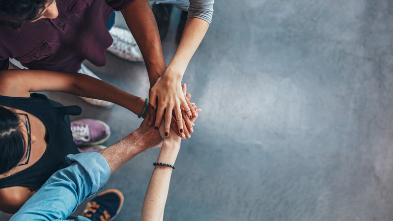 Oberansicht: Hände liegen im Kreis aufeinander