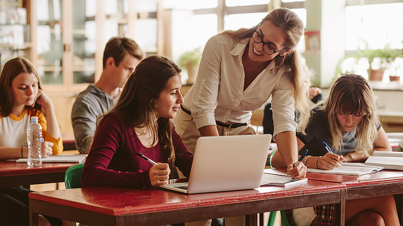 Lehrerin im Unterricht bei Schülerin mit Laptop