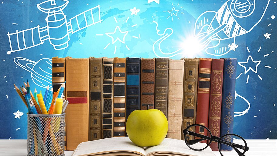 Reihe von Büchern, Bleistiften, Brillen, grüner Apfel auf offenem Buch