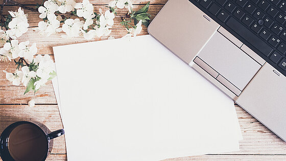 Arbeitsraum mit Laptop und Frühlingsblumen 