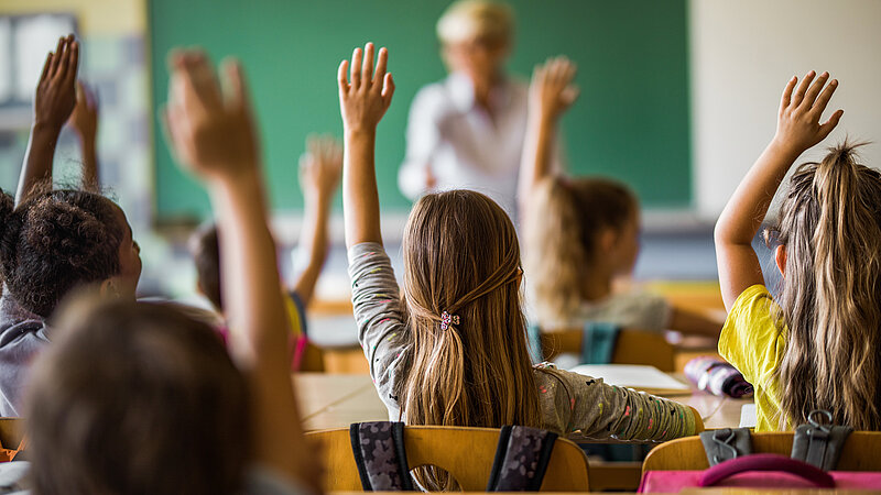 Kinder melden sich im Unterricht