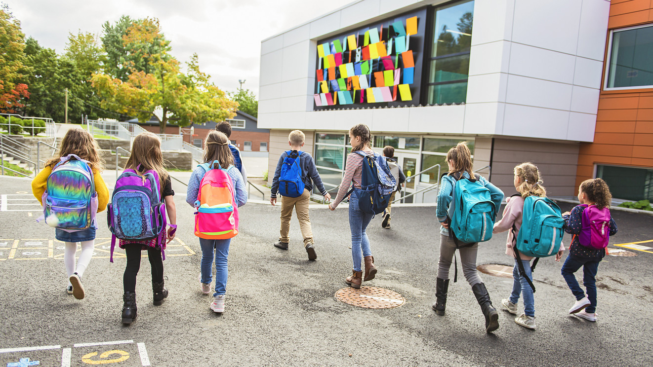 Rückansicht: Gruppe von Kindern gehen in die Schule