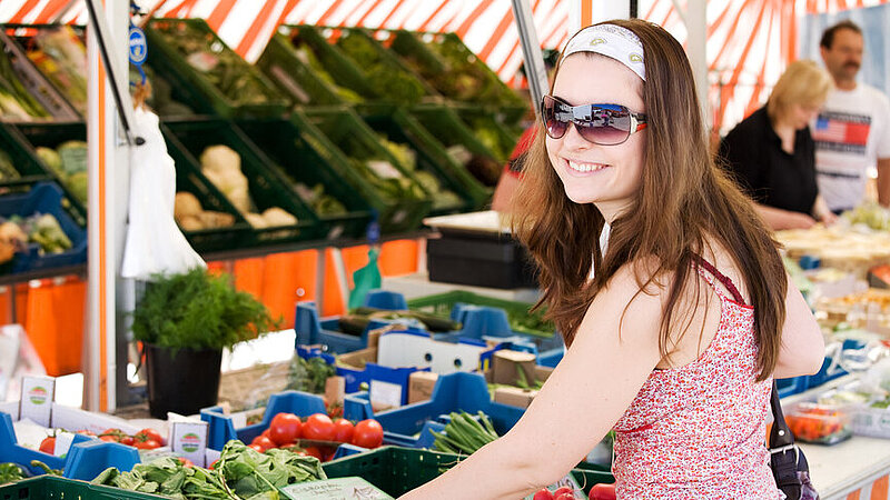 Frau mit Sonnenbrille steht am Gemüsestand