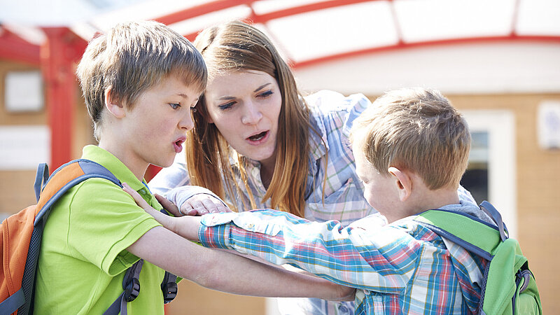 Lehrerin zwischen streitenden Schülern