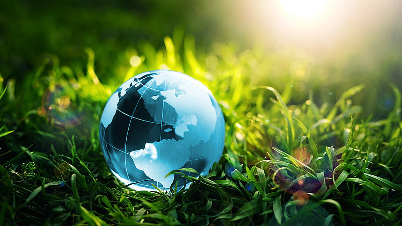 Kleine Erdkugel liegt im Gras als Symbol für eine saubere Umwelt