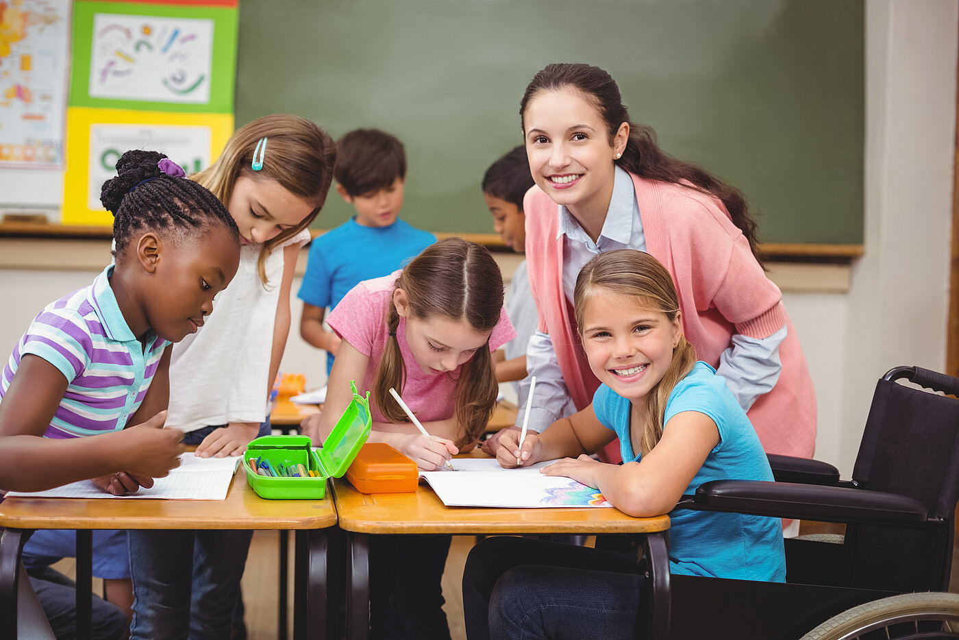 Mehrere junge Schülerinnen mit Lehrerin an Gruppenarbeitstisch