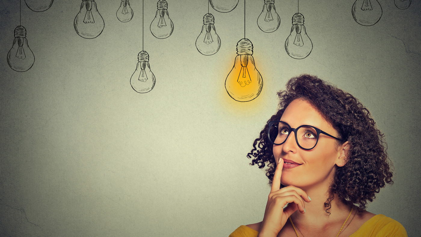 woman in glasses looking up with light idea bulb