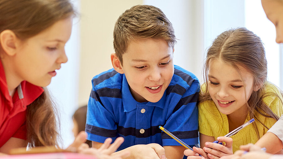 Junge Schülerinnen und Schüler, die gemeinsam etwas erarbeiten/aufschreiben