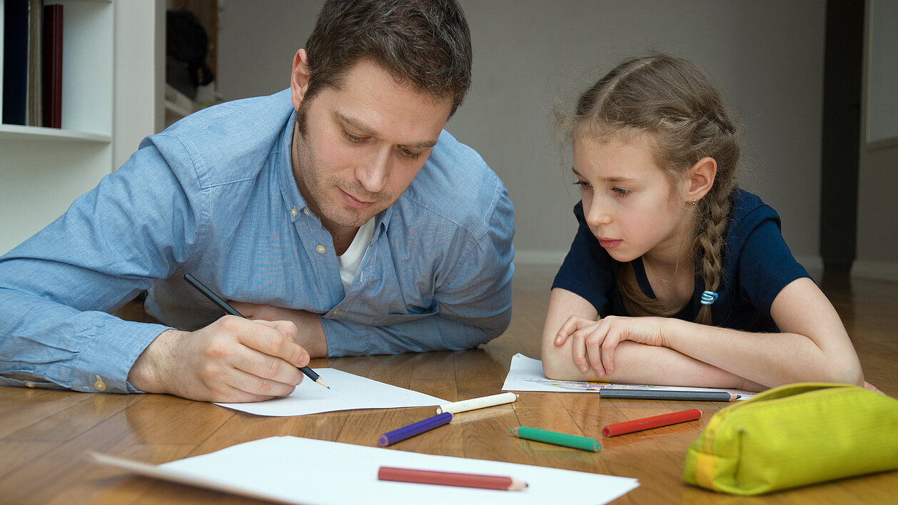 Vater und Tochter zeichnen/schreiben gemeinsam
